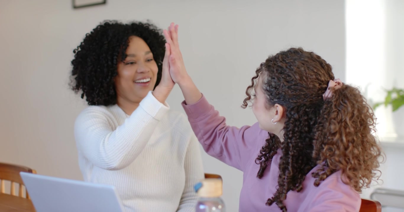 African American woman and teen girl at home with laptop, girl typing, adult helping, highfiving