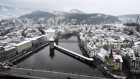 aerial flyover towards kappelbrücke in lucerne, switzerland as the city is covered in snow in winter