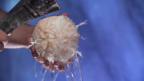 Hand-with-Knife-Chop-Whole-Coconut,-Close-Up