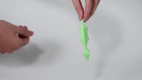 hands stretching a green dinosaur toy