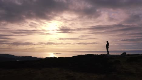 Silueta-De-Hombre-De-Pie-Frente-A-La-Impresionante-Vista-De-La-Puesta-De-Sol-Junto-Al-Mar-De-La-Costa-En-Mull,-Escocia