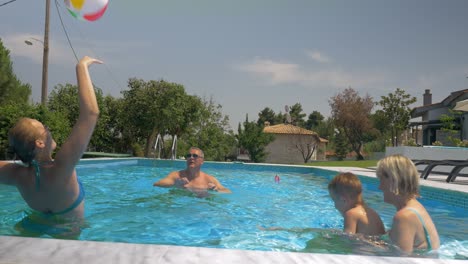 Vereinte-Familie-Spielt-Aufblasbaren-Ball-Im-Heimischen-Pool