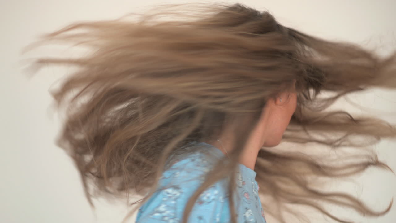 青いシャツを着てくるくる回るブルネットの女性