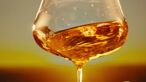 orange or white wine bottle and glass against a sunset in a peaceful vineyard, pouring of ecological natural wine.
