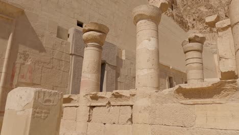 Pan-shot-along-sandstone-Columns-ruins-in-the-Temple-of-Hatshepsut-during-sunlight,-Egypt