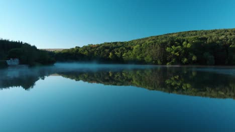 Early-morning-low-drone-shot-over-glossy-lake-and-some-fog-1