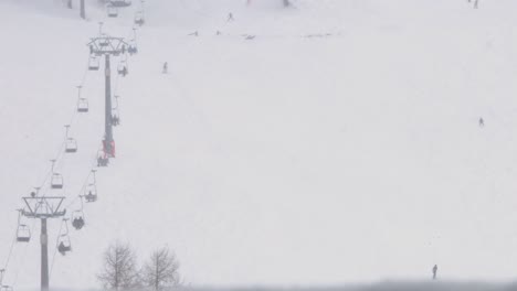 Timelapse-shot-of-a-chair-lift-and-skiers-who-are-skiing-down-a-hill