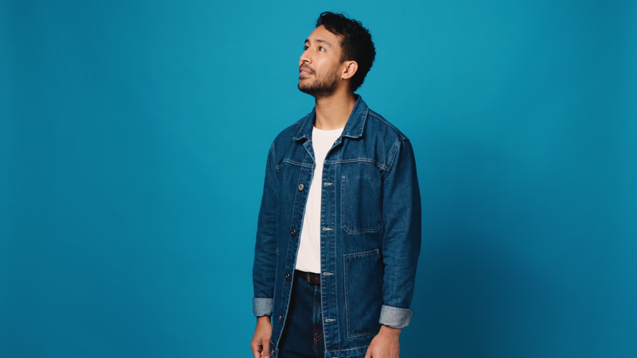 Man in denim jacket smiling against a blue background