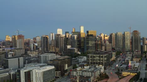 Last-light-of-day-hitting-top-of-high-rise-buildings-of-Seattle,-aerial-sideways