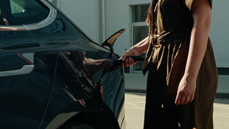 mujer cargando un coche eléctrico