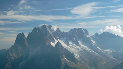 Snow-capped-rocky-mountains-with-blue-sky-and-clouds-with-a-natural-light-in-the-alps