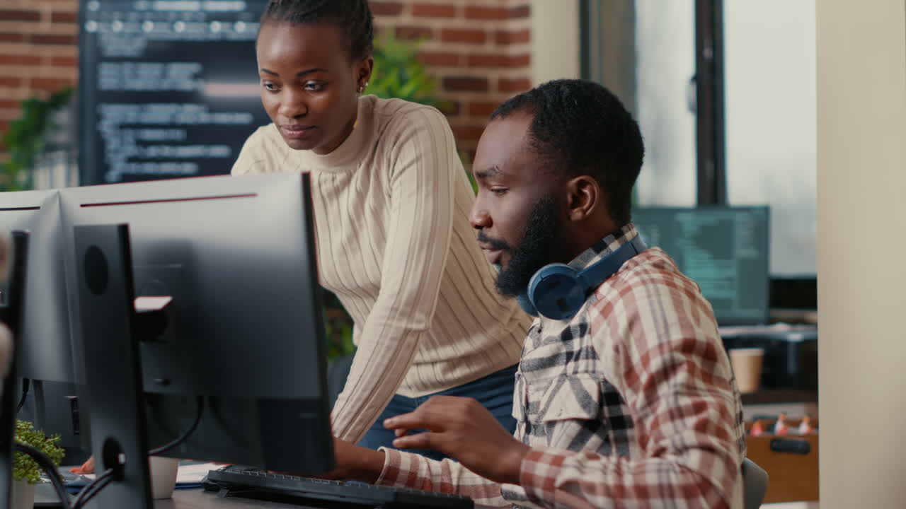 Relaxed software developer wearing wireless headphones smiling working looking at computer screen