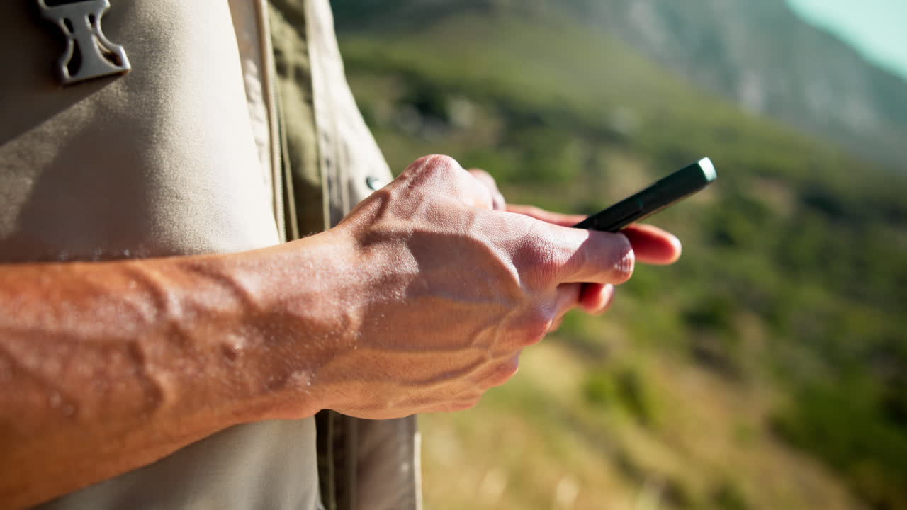 Primo piano di una mano che usa lo smartphone all'aperto nella natura
