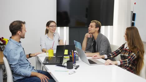 Jóvenes-Empresarios-Creativos-Con-Computadoras-Portátiles-En-La-Oficina-Discutiendo-El-Proyecto