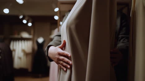 a person's hands adjusting fabric on a mannequin in a fashion store