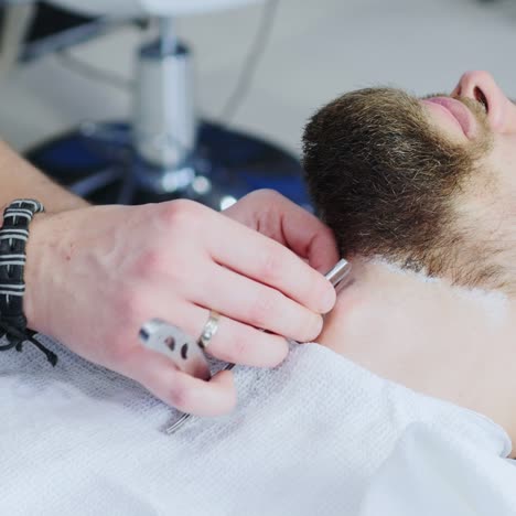 barbero pone toques finales en la barba con navaja