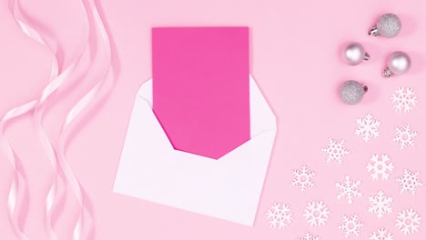 cintas románticas pastel, regalos de plata y copos de nieve aparecen con papel rosado en sobre con tema rosado pastel.