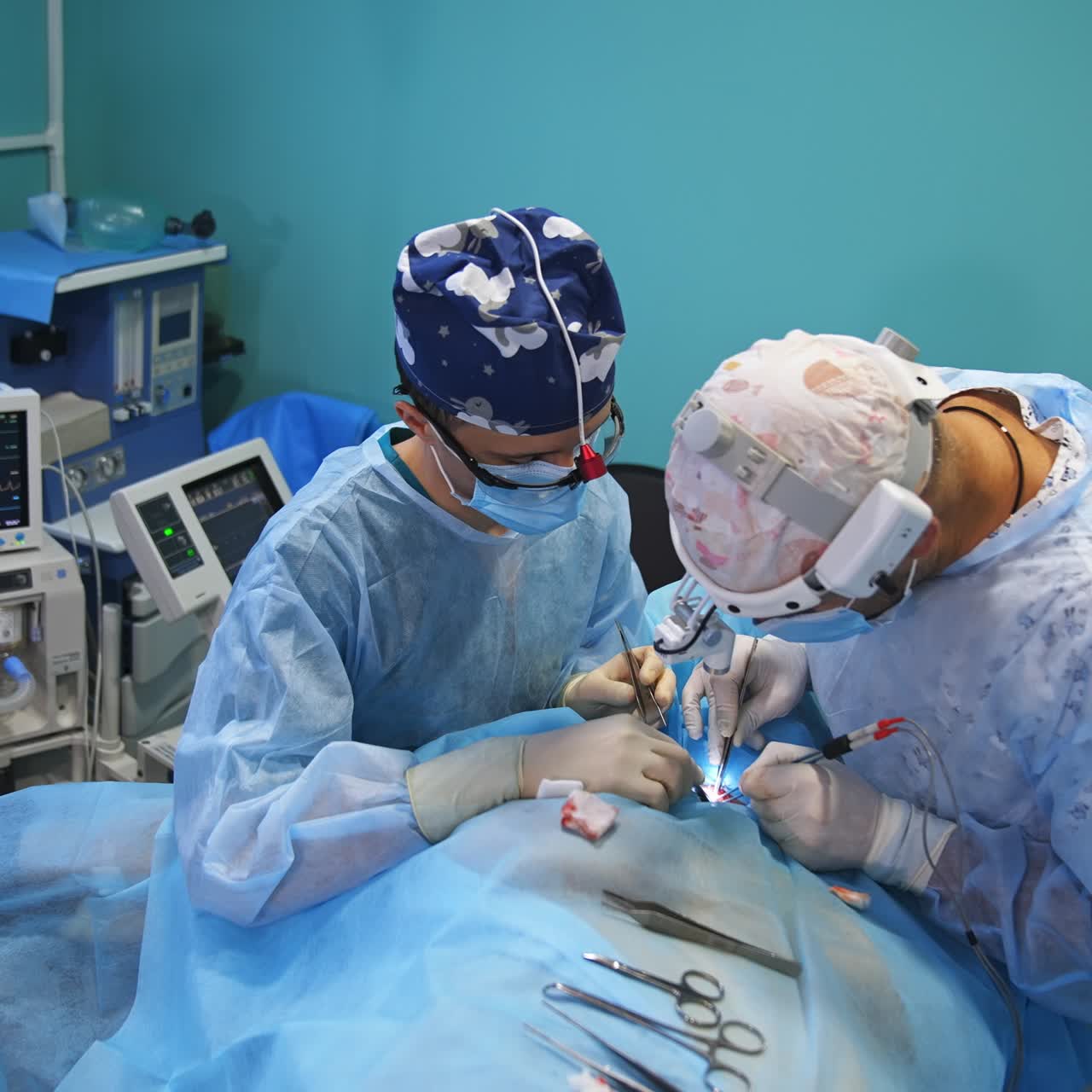 Delicate surgery work using metal tools and electric instruments. Two doctors collaborating in surgery room. High angle view