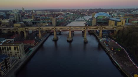 Aerial-drone-video-of-Newcastle-Quayside-at-sunset,-overlooking-the-Tyne-Bridge,-Millennium-Bridge-and-The-Sage