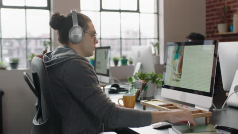joven diseñador de negocios caucásico trabajando en un proyecto de diseño gráfico usando una computadora escuchando música disfrutando de escribir notas intercambiando ideas en un lugar de trabajo de oficina relajado