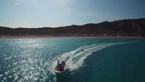toma aérea de un tirón inflable remolcable por un pequeño bote en el mar de cortez