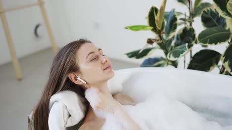 woman in bath listen music in airpods