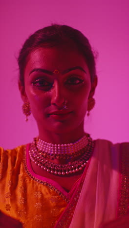 vertical video close up on face of female kathak dancer performing dance wearing traditional indian dress against purple background 4