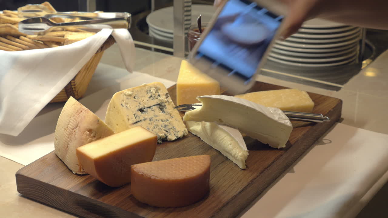 las manos tomando fotos de pedazos de queso