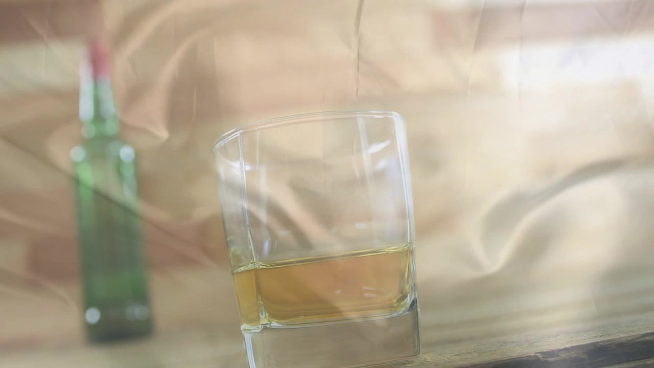 Bicchiere di whisky con bottiglia sfocata sullo sfondo