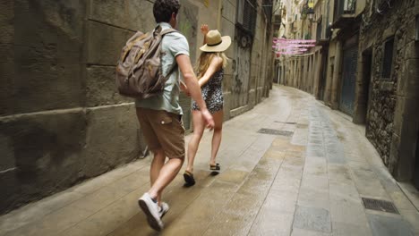 4k video footage of an attractive young woman running through the streets of barcelona while holding her boyfriend's hand