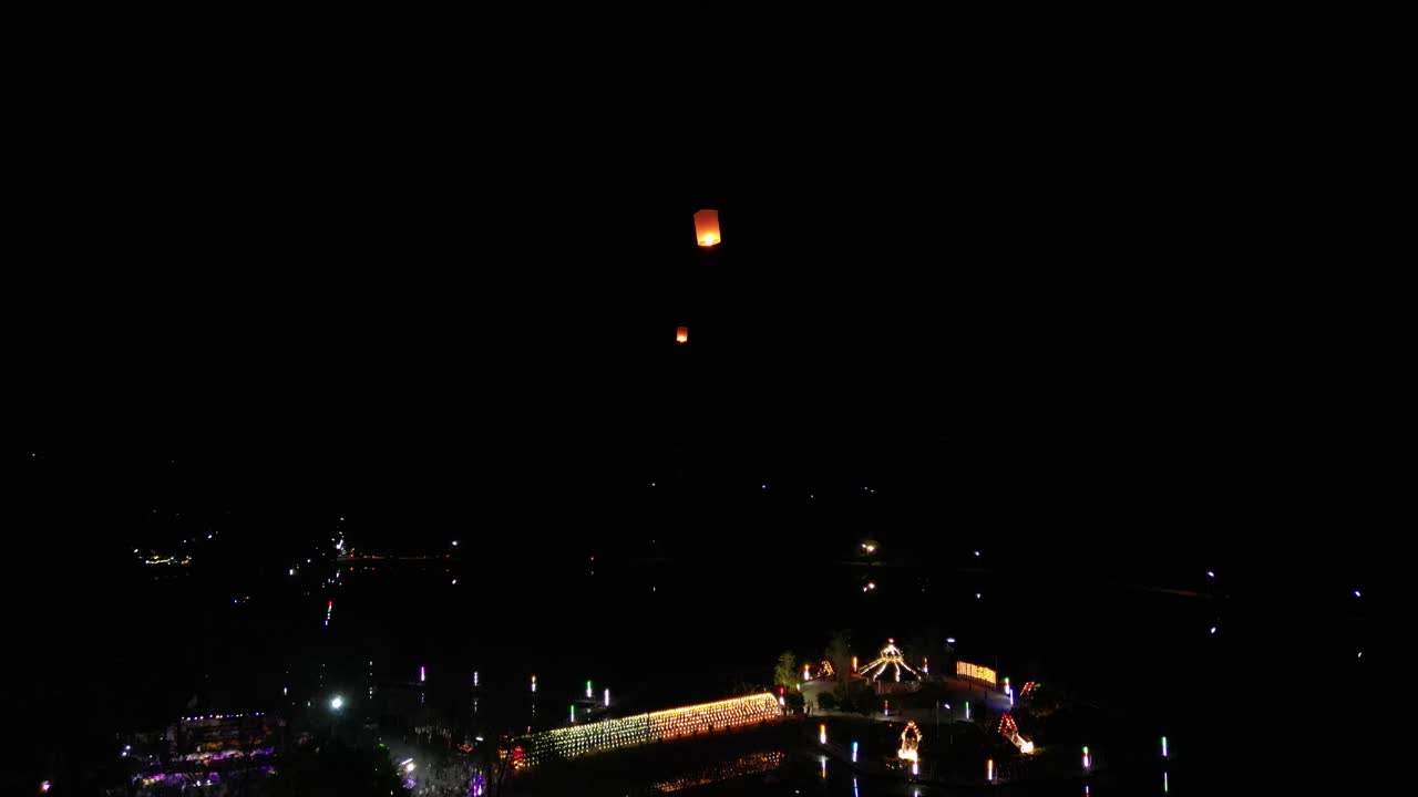 밤하늘을 날아가는 떠오르는 등불을 따라 드론 샷