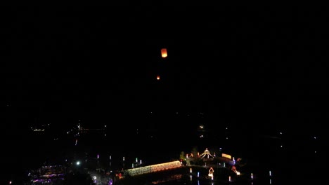 Drone-shot-following-rising-floating-lanterns-flying-through-night-sky