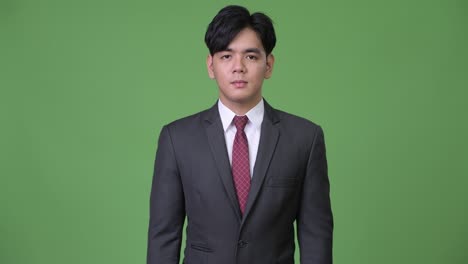 young handsome asian businessman against green background