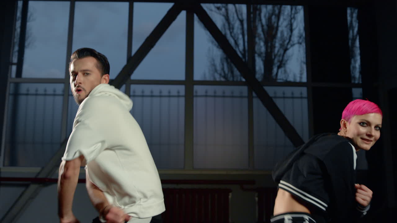 도시 댄서들이 수업에서 즐겁게 춤을 추고 있습니다. 어두운 인테리어에서 춤을 추는 유쾌한 커플.