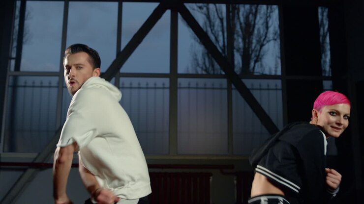 Urban dancers having fun in class. Cheerful couple dancing in dark interior.