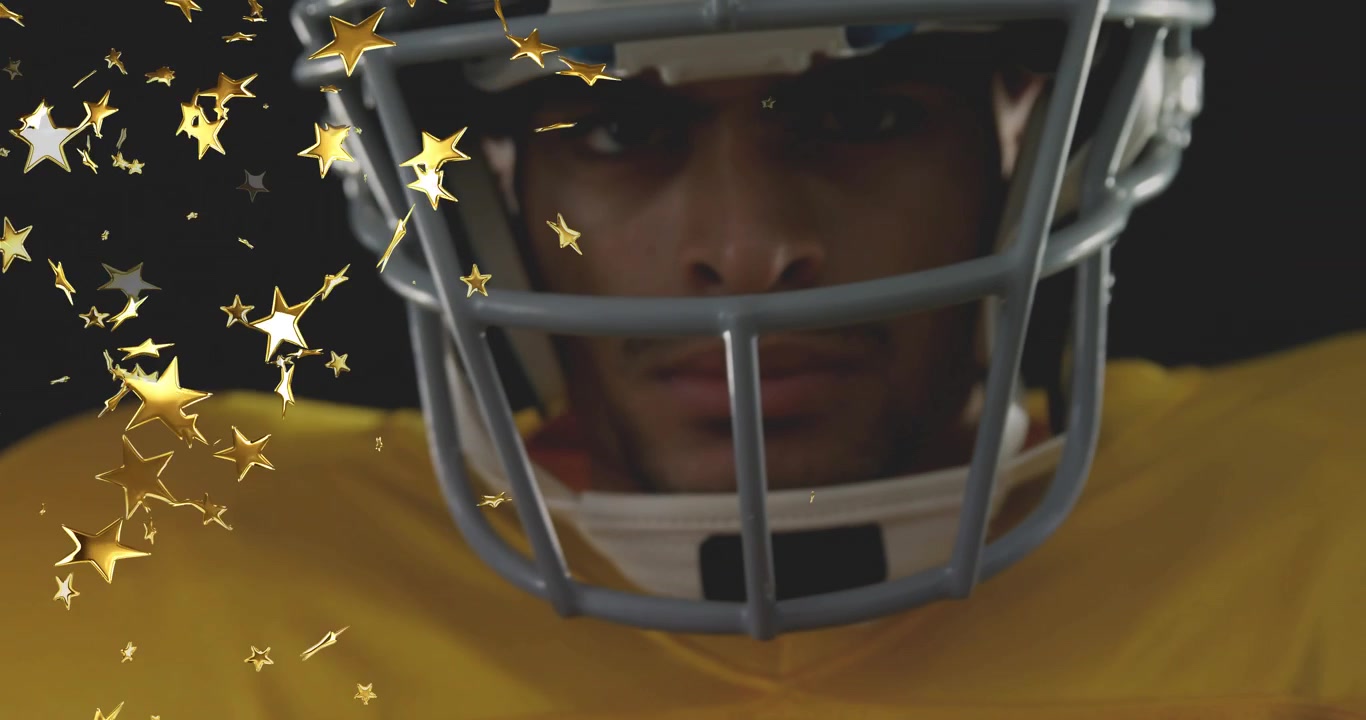 Giocatore che tiene un pallone da football americano mentre la telecamera si inclina verso l'alto, con stelle dorate che attraversano la maschera protettiva per una pubblicità sportiva.