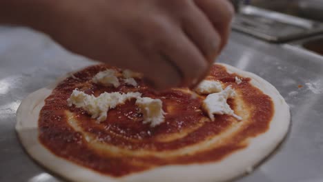 adding mozzarella cheese topping onto the neapolitan pizza dough