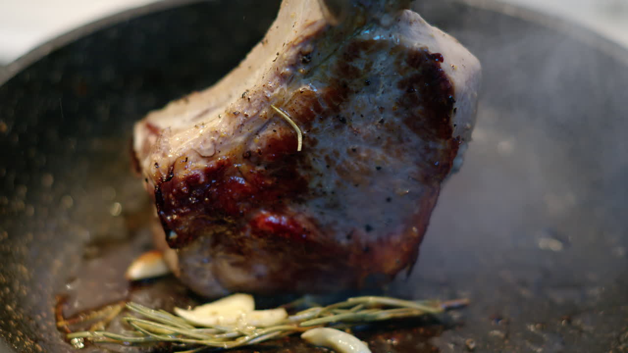 Cooked juicy steak meat beef being prepared with rosemary and garlic