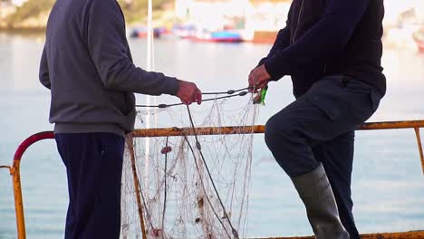 two men handling a fishing net on a sunny day