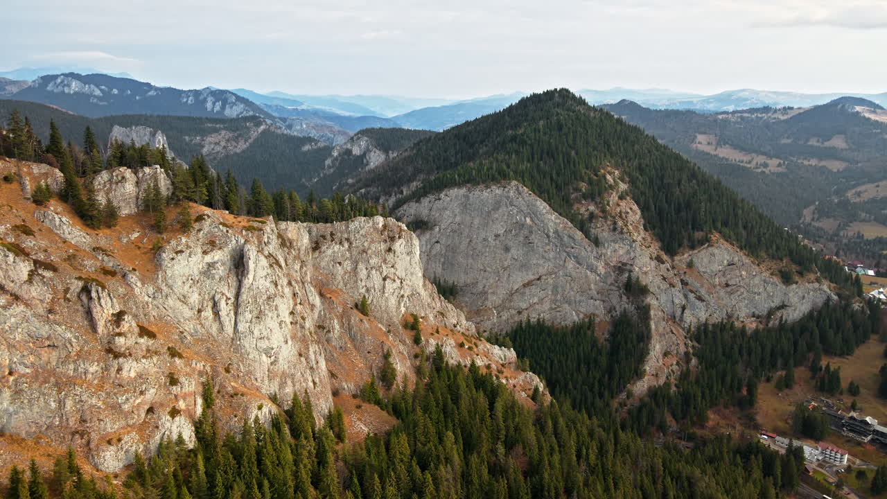 Aerial drone view of nature in Romania. Carpathian mountains, rocky hills covered with lush forest, road in the valley