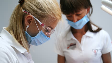 medics in masks at their work. portraits of dentist and assistant focused on procedure. close up.