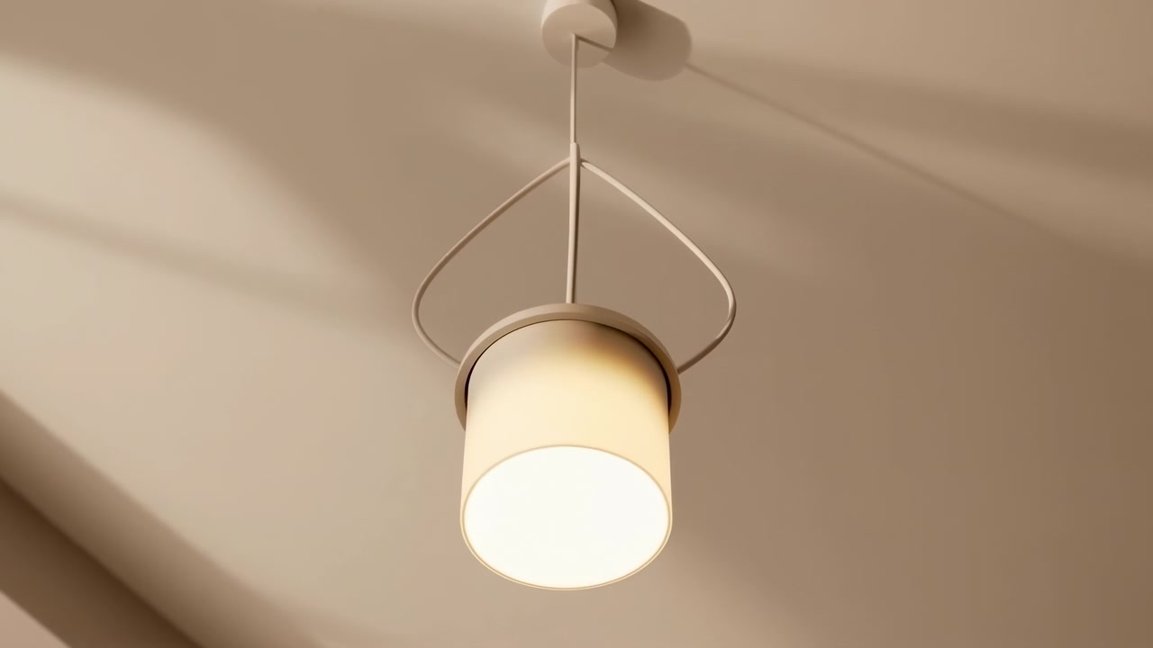Low-angle view of modern cylindrical pendant light suspended from smooth beige ceiling, emitting warm frosted glow while gentle rotation and downward tilt create shifting shadows across surrounding
