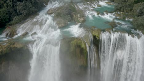 Misty-tendrils-from-waterfall-cascading-turquoise-water-in-Mexico-Jungle