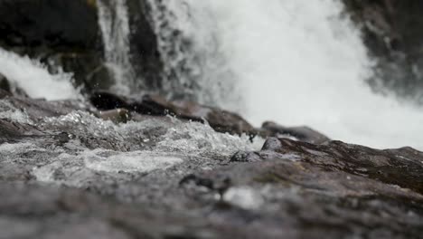 Una-Toma-Macro-En-Cámara-Lenta-De-Agua-Que-Fluye-Con-Las-Cataratas-Lucia-Que-Se-Avecinan-En-El-Fondo-En-Vancouver,-Washington