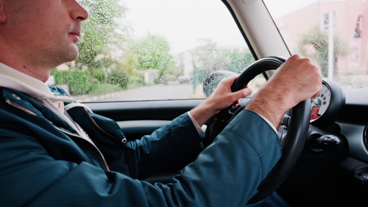 Close up of a man driving a car on the road in the rain