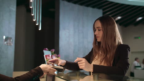 businesswoman paying bill with mobile phone at hotel reception