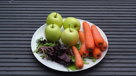 fruit and veg on a plate outside colourful apples carrots lettuce