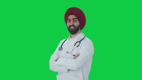 portrait of happy sikh indian doctor standing crossed hands green screen