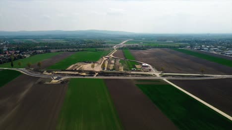 AERIAL---Farmland-around-railroad-construction,-Baden,-Austria,-wide-shot