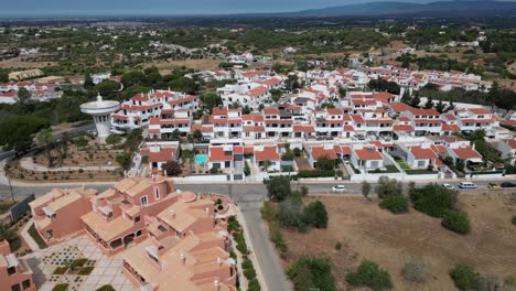 drone flying forward over colorful town of porches in algarve portugal white houses and church